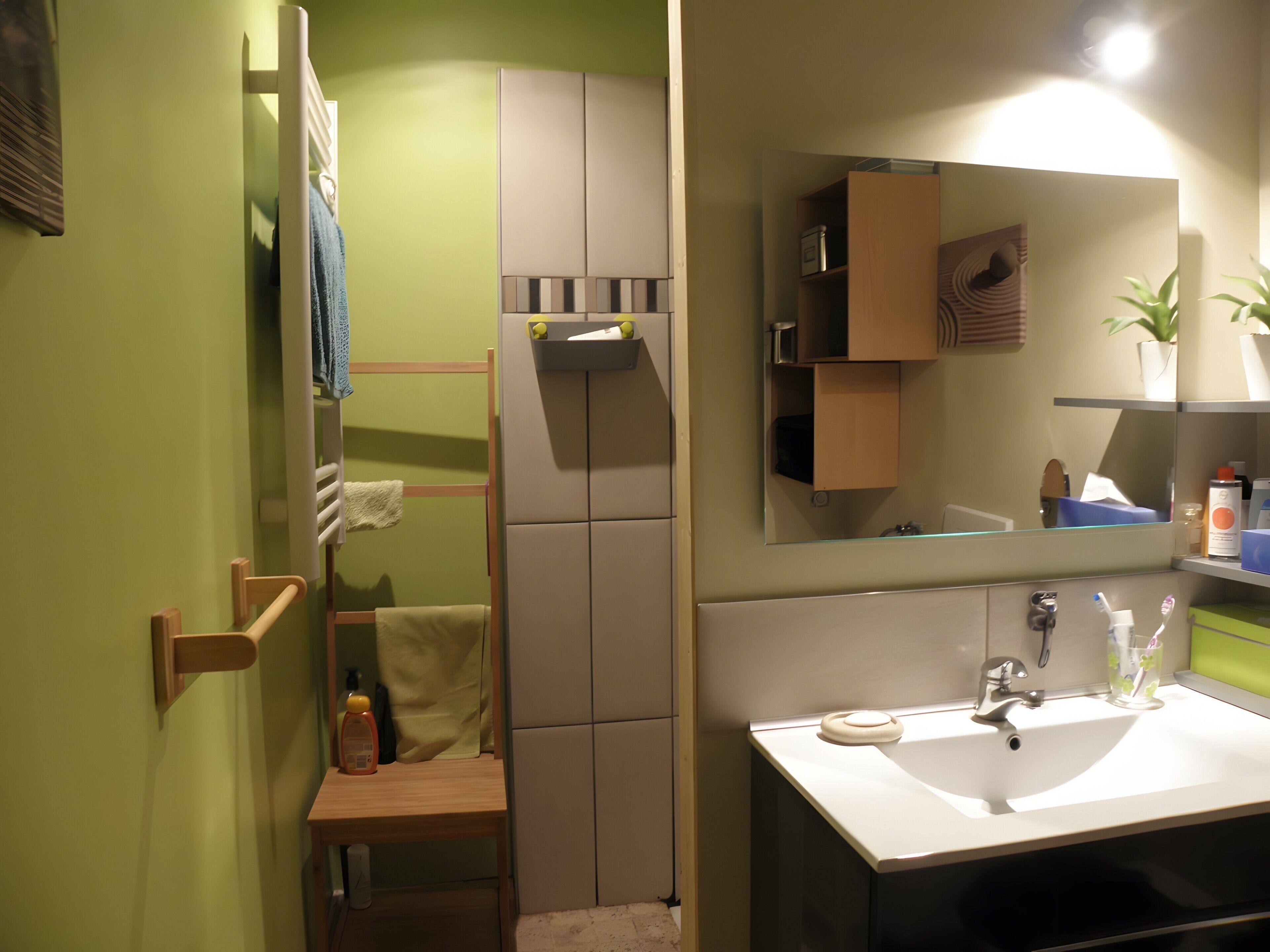 A bathroom with a sink, mirror, towel rack, and a shower area.