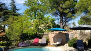 Una piscina con lettini e un pergolato.