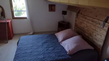 A bedroom with a bed, a wooden headboard, a nightstand, a dresser, and a window.