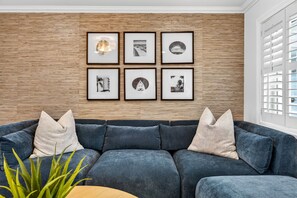 A modern living room with a sectional sofa, a wooden wall, and framed pictures.