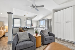 A modern kitchen with white cabinets, a stainless steel refrigerator, and a ceiling fan.