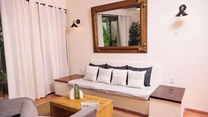 A living room with a sofa, a coffee table, a lamp, and a mirror.