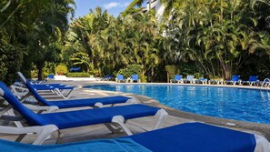 Un espace aménagé au bord de la piscine, avec des chaises longues et des palmiers.