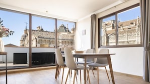 A dining area with a table and chairs, large windows with a view of historic buildings, and a modern ceiling design. - Penthouse with terrace in central Granada, stunning views (Granada)