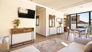 A modern living room with a flat-screen TV, a wooden console table, and a large window overlooking a terrace. - Penthouse with terrace in central Granada, stunning views (Granada)
