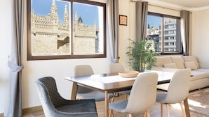 A modern living room with a dining area, large windows with a view of a historic building, and a potted plant. - Penthouse with terrace in central Granada, stunning views (Granada)