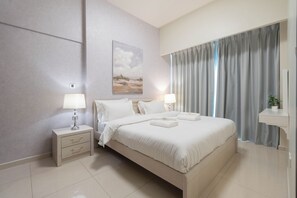 A hotel room with a large bed, a nightstand with a lamp, a painting on the wall, and a window with curtains. - Dubai Luxury 2BR - Burj Khalifa View (Dubai)