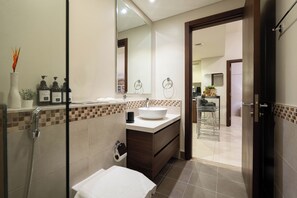 A modern bathroom with a large mirror, a white sink, and a shower area. - Dubai Luxury 2BR - Burj Khalifa View (Dubai)