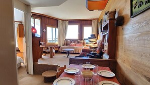 A dining area with a table set for four, a sofa, and a lamp in the background. - Avoriaz - Cozy apartment for 6, near ski slopes (Avoriaz)