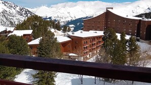 Une station de montagne dotée d’un grand bâtiment avec des balcons, le tout surplombant un paysage enneigé.