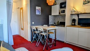 Une cuisine compacte comprenant un coin repas, un four à micro-ondes, une machine à café et un téléviseur.
