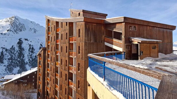 Un bâtiment en bois doté de nombreux balcons et d’une enseigne sur laquelle on peut lire « LE Fond Blanc ».