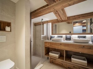 A modern bathroom with a wooden vanity, a large mirror, and a glass shower enclosure. - Modern chalet in Courchevel with sauna and jacuzzi (Courchevel 1550)
