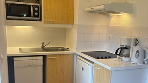 Eine kompakte Küche mit Mikrowelle, Spüle, Geschirrspüler, Herd und Kaffeemaschine.