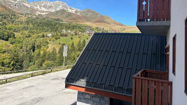 Ein Gebäude mit einem geneigten Dach und einem Balkon mit Holzgeländer.