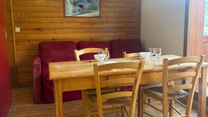 Ein Holzespeisesaal mit vier Stühlen, einem roten Sofa und einem Gemälde an der Wand.
