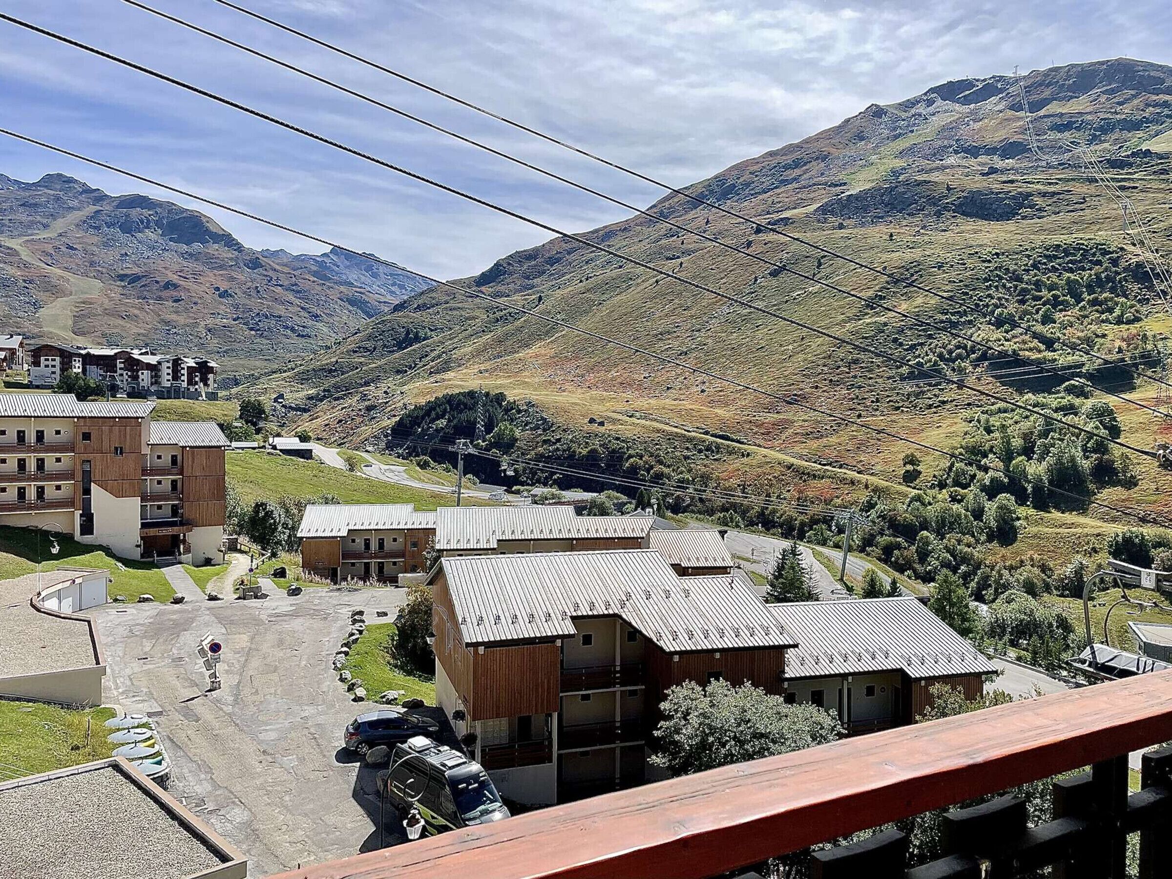 Un pueblo de montaña con edificios modernos, una carretera pavimentada y vistas de las colinas circundantes.