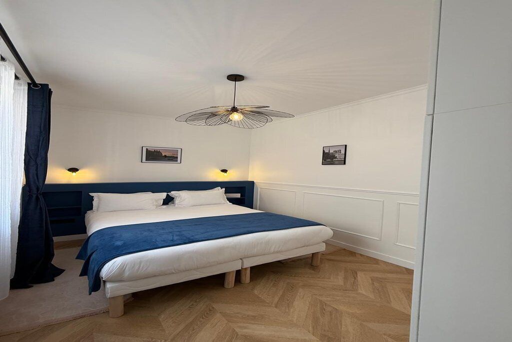 A bedroom with a bed, a ceiling fan, and two wall-mounted lights.