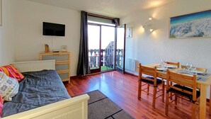Una stanza con un letto, un tavolo apparecchiato per mangiare, una TV e un balcone con vista.