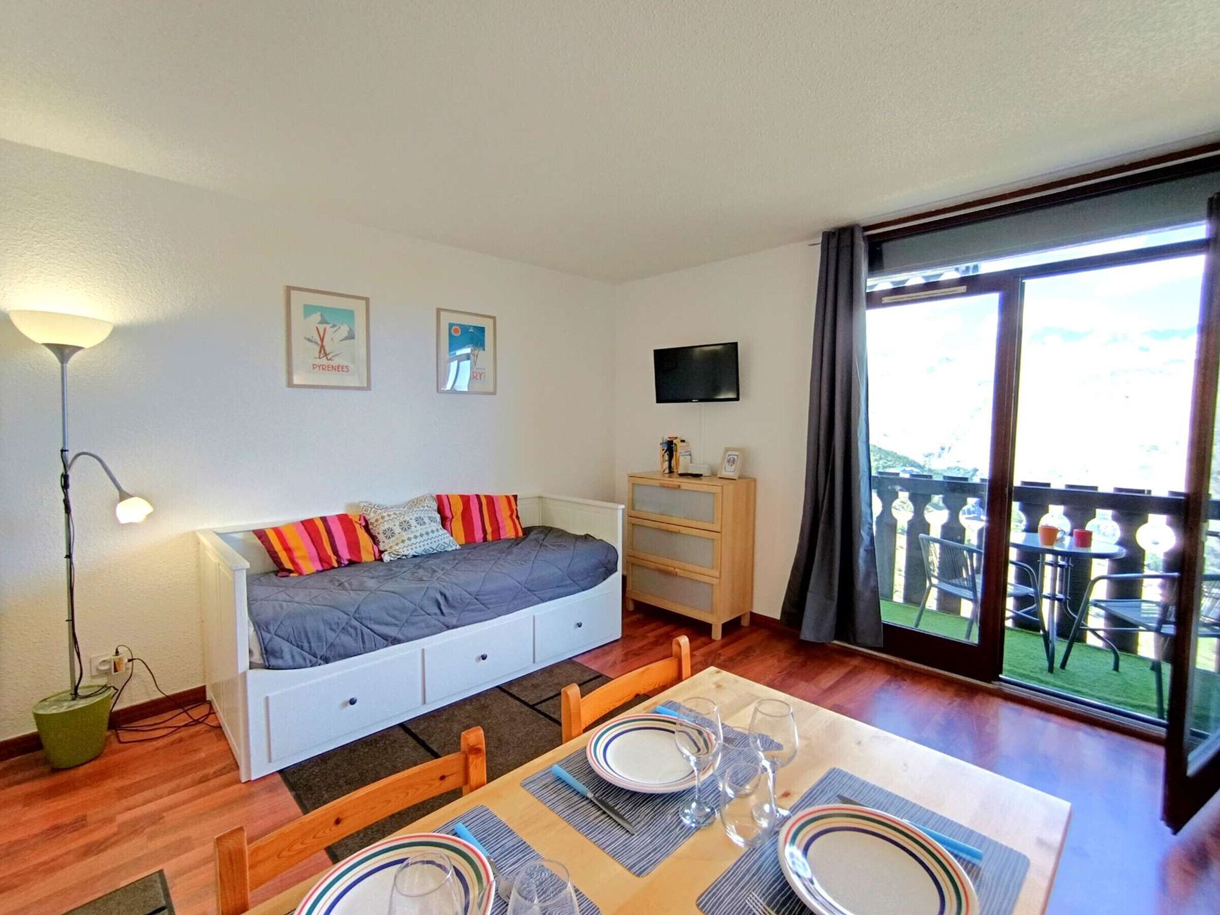 A cozy room with a bed, a TV, and a balcony with outdoor furniture.