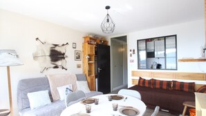 Een woonkamer met een ronde eettafel gedekt voor vier personen, een grijze bank, een bruine bank en een dierenhuid aan de muur.