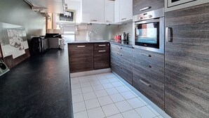 Una cocina moderna con armarios de madera oscura, horno empotrado y salpicadero de azulejos.