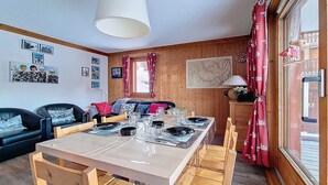 Un coin repas avec une table en bois dressée pour quatre personnes, entourée de chaises en bois.