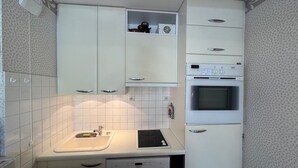 A compact kitchen with white cabinets, a built-in oven, and a dishwasher. - Bright apartment close to slopes, balcony and parking (La Salle-les-Alpes)