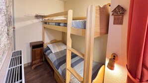 A bunk bed room with a small wooden cabinet and a radiator. - Bright apartment close to slopes, balcony and parking (La Salle-les-Alpes)