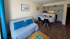 A cozy living area with a patterned sofa, a dining table with chairs, and a kitchen in the background. - Bright apartment close to slopes, balcony and parking (La Salle-les-Alpes)