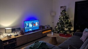 Un salon avec un téléviseur, un sapin de Noël et un canapé.