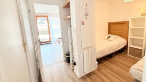 Een slaapkamer met een bed, een houten hoofdbord, een witte kledingkast en een deur naar een balkon.