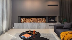 Ein modernes Wohnzimmer mit Kamin, einer Couch und einem Couchtisch mit Büchern und Kerzen.
