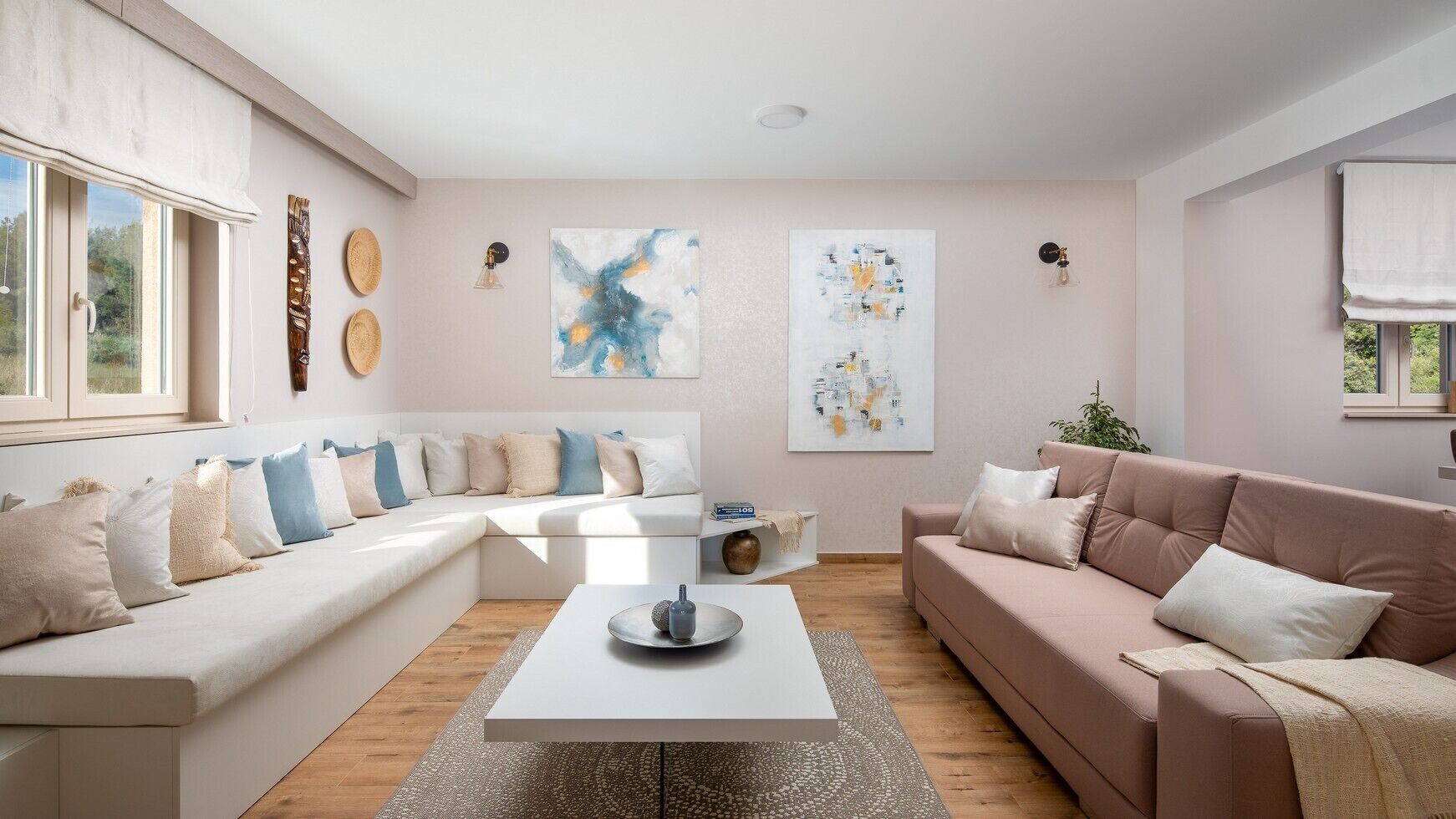 Un salon moderne avec un canapé d’angle, une table basse et des œuvres d’art abstraites accrochées aux murs.