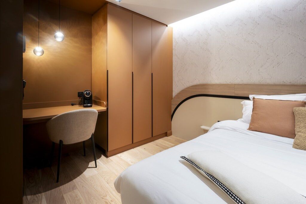 A compact hotel room with a bed, a desk, and a chair.