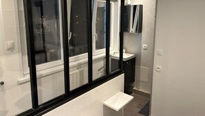A modern bathroom with a large window, a white sink, and a mirror. - Face à La Mer Gravelines  (Gravelines)