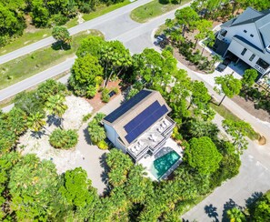 Vista aérea de una casa con techo solar, piscina y abundante vegetación.