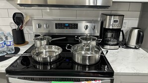 Une cuisine équipée d’une cuisinière, de casseroles, d’une machine à café et de bouteilles d’eau.