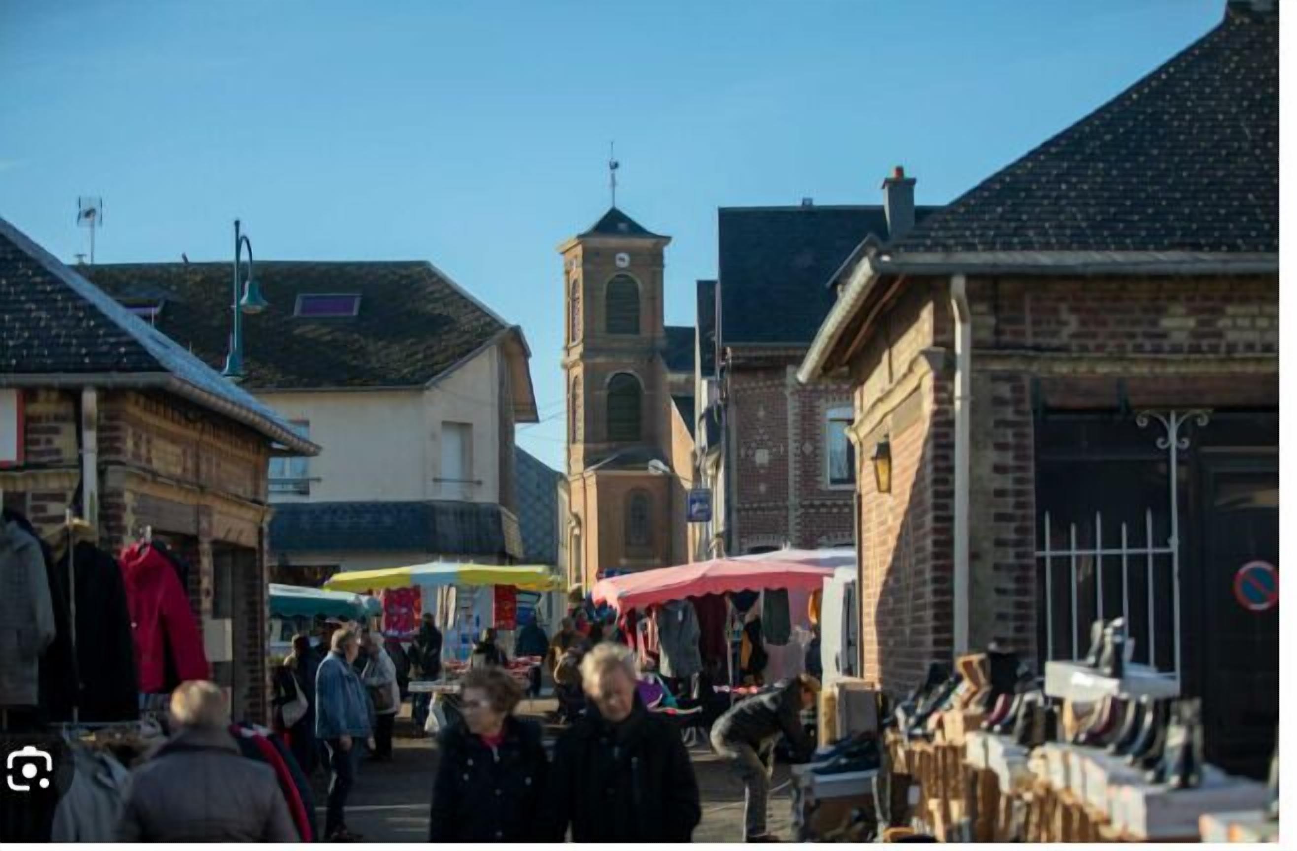 A bustling street market with various stalls and a prominent clock tower in the background.