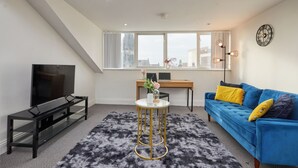 Ein modernes Wohnzimmer mit Fernseher, Sofa und Schreibtisch.