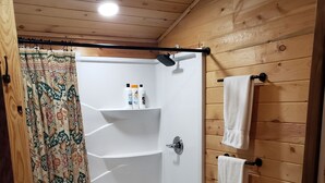 Bagno con rivestimenti in legno, doccia, water e porta asciugamani.