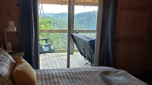 Una camera da letto con un letto grande, una scrivania e vista su un balcone con tavolo e sedie.