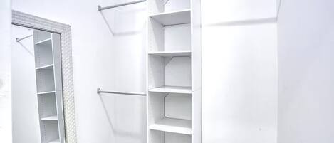 A white closet with multiple shelves and a hanging rod.