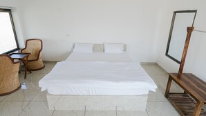 Een hotelkamer met een groot bed, een bureau met stoel en een televisie op een standaard.