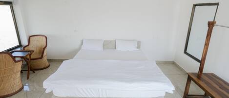 Et hotelværelse med en stor seng, et skrivebord med stol og et fjernsyn på et stativ.