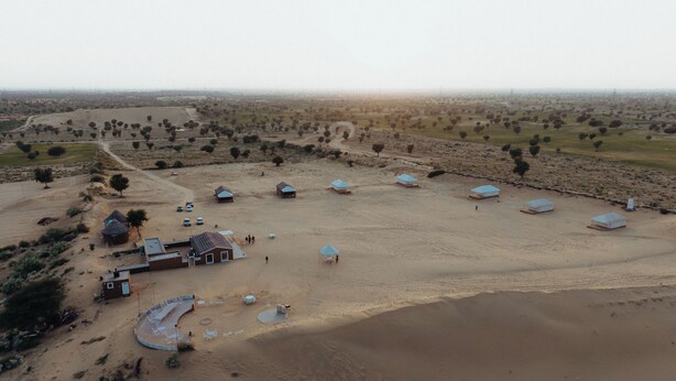 Luchtbeeld van een woestijndorp met verschillende tenten en enkele gebouwen.