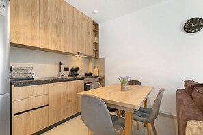 Una cocina moderna con armarios de madera, una mesa de comedor con sillas y un reloj en la pared.
