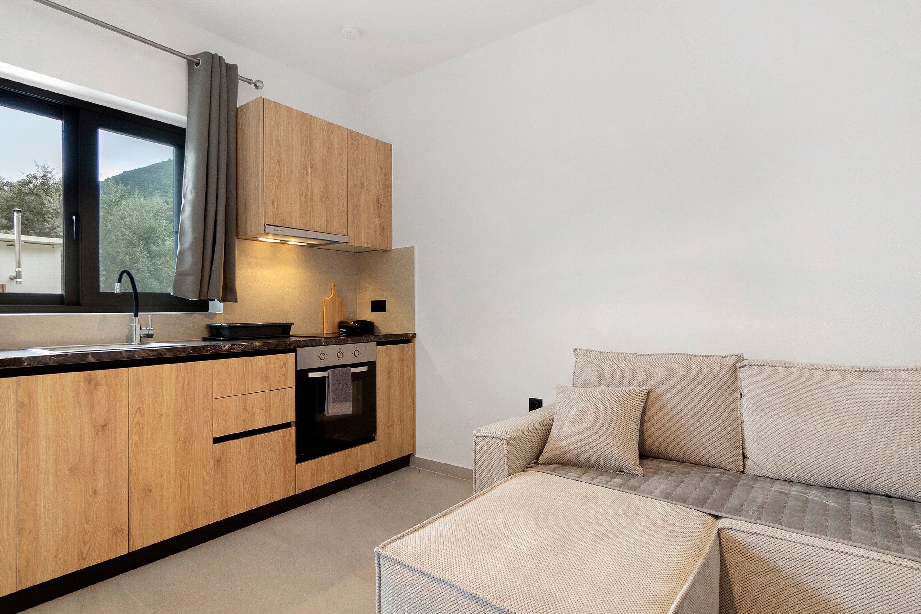 Une cuisine moderne avec des meubles en bois, un four encastré et une fenêtre avec un rideau.