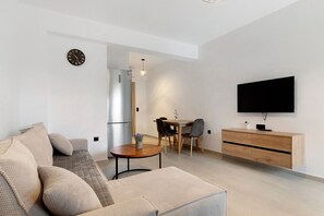 Una sala de estar moderna con un sofá, una mesa de comedor, sillas, un televisor y un mueble de madera.