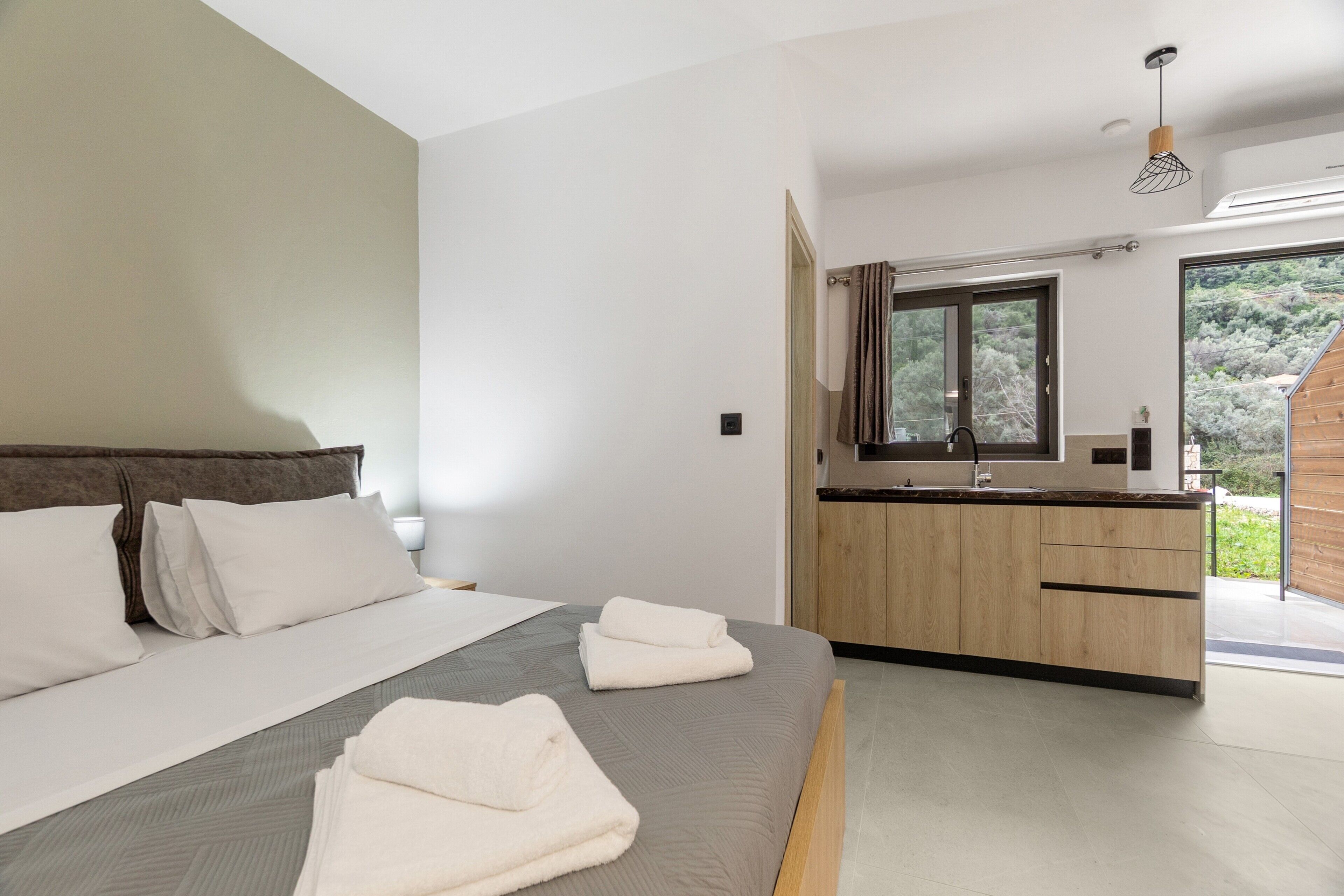 A modern bedroom with a large bed, a wooden cabinet, and a view of the outdoors.